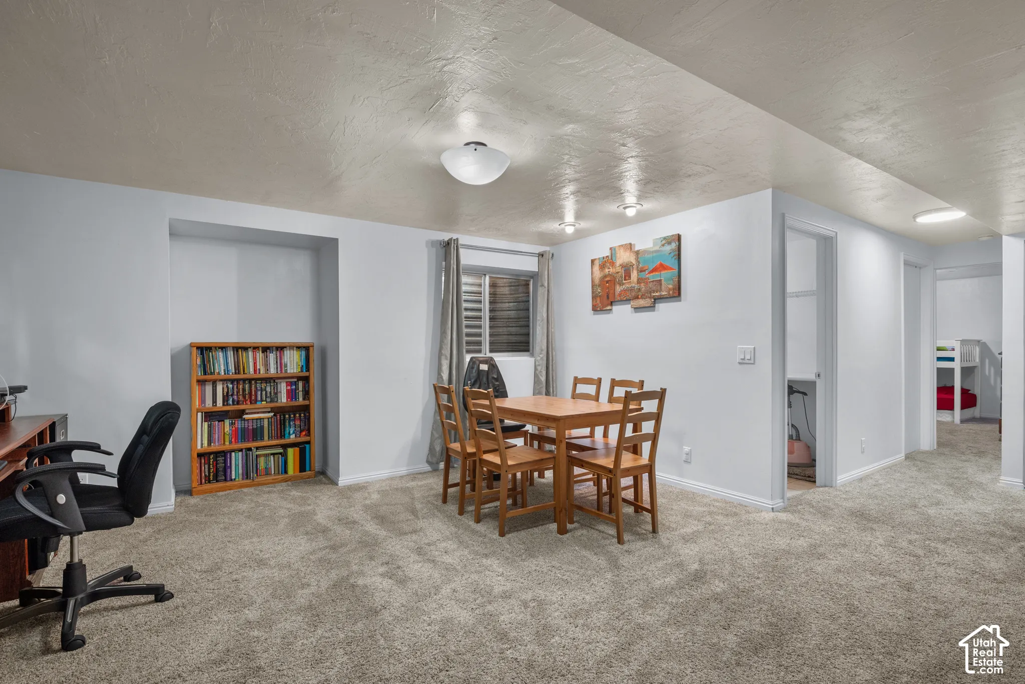 Neutral-toned interior space featuring wall-to-wall carpeting, recessed ceiling lighting, a dedicated recessed shelving niche, and a neutral color palette