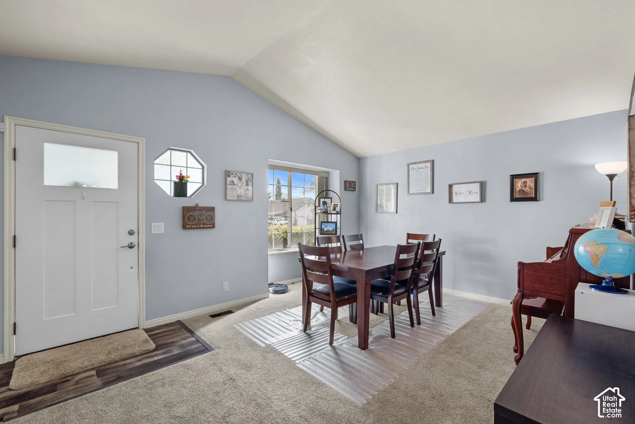 Vaulted ceilings, paneled entry door with glass inlay, hexagonal accent window, and wood-finish entry flooring