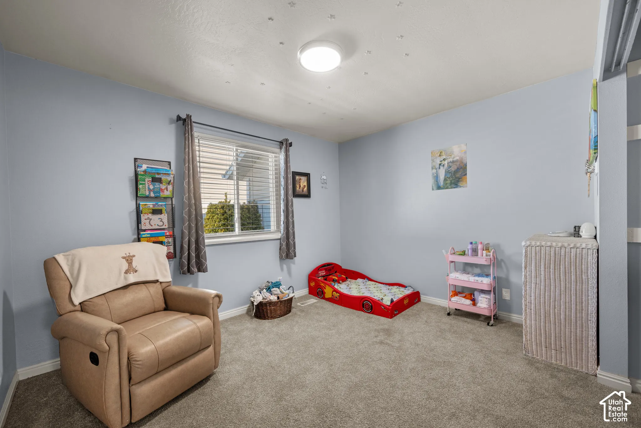 Room featuring neutral-toned carpeting, a sliding window with horizontal blinds, and a central ceiling-mounted light fixture