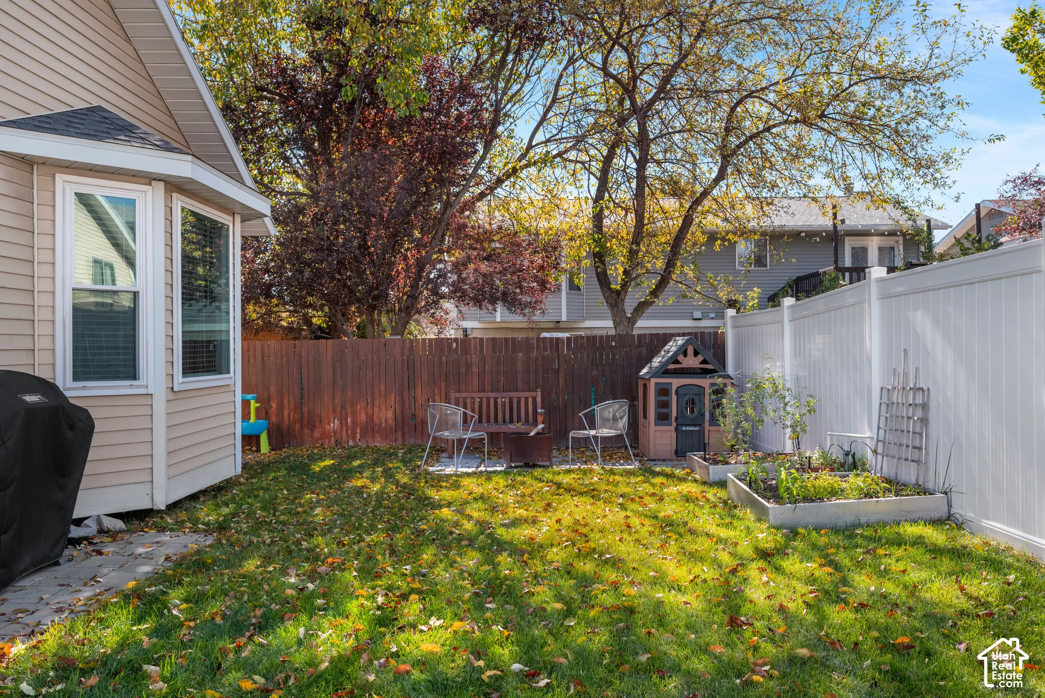 Backyard featuring a grass lawn, perimeter wood fencing, white vinyl privacy fencing, and a raised garden bed