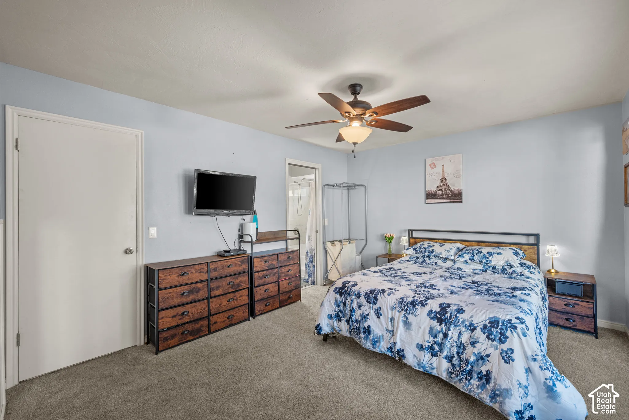 Room featuring neutral-toned carpeting, a central ceiling fan with integrated lighting, and a six-panel interior door