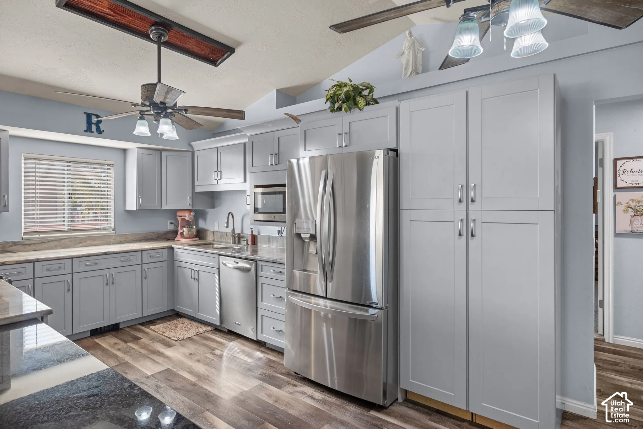 Kitchen featuring light gray shaker-style cabinetry, wood-finish flooring, stainless steel appliances, and stone-look countertops