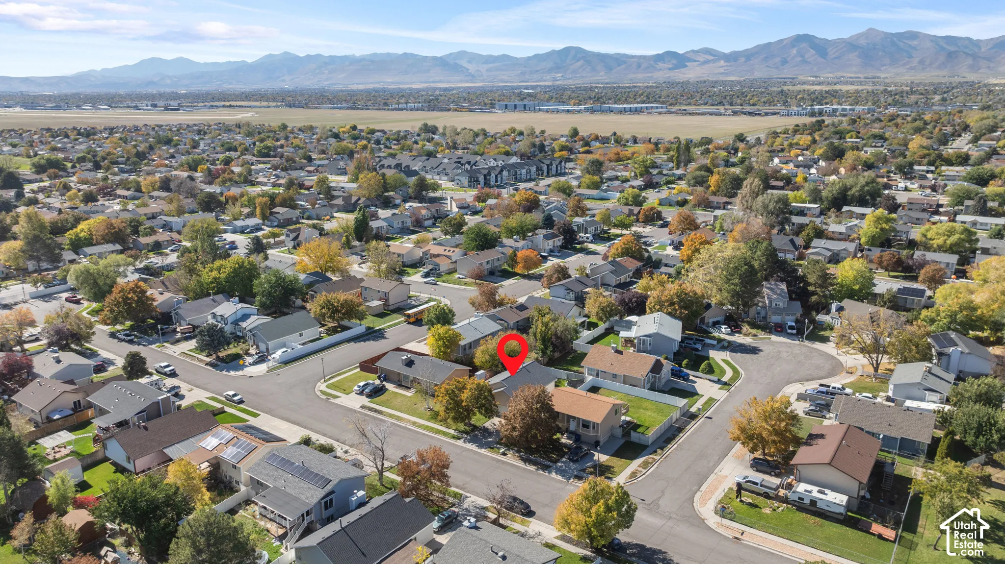 Aerial perspective of a residential property situated in a suburban setting with a prominent mountain range backdrop