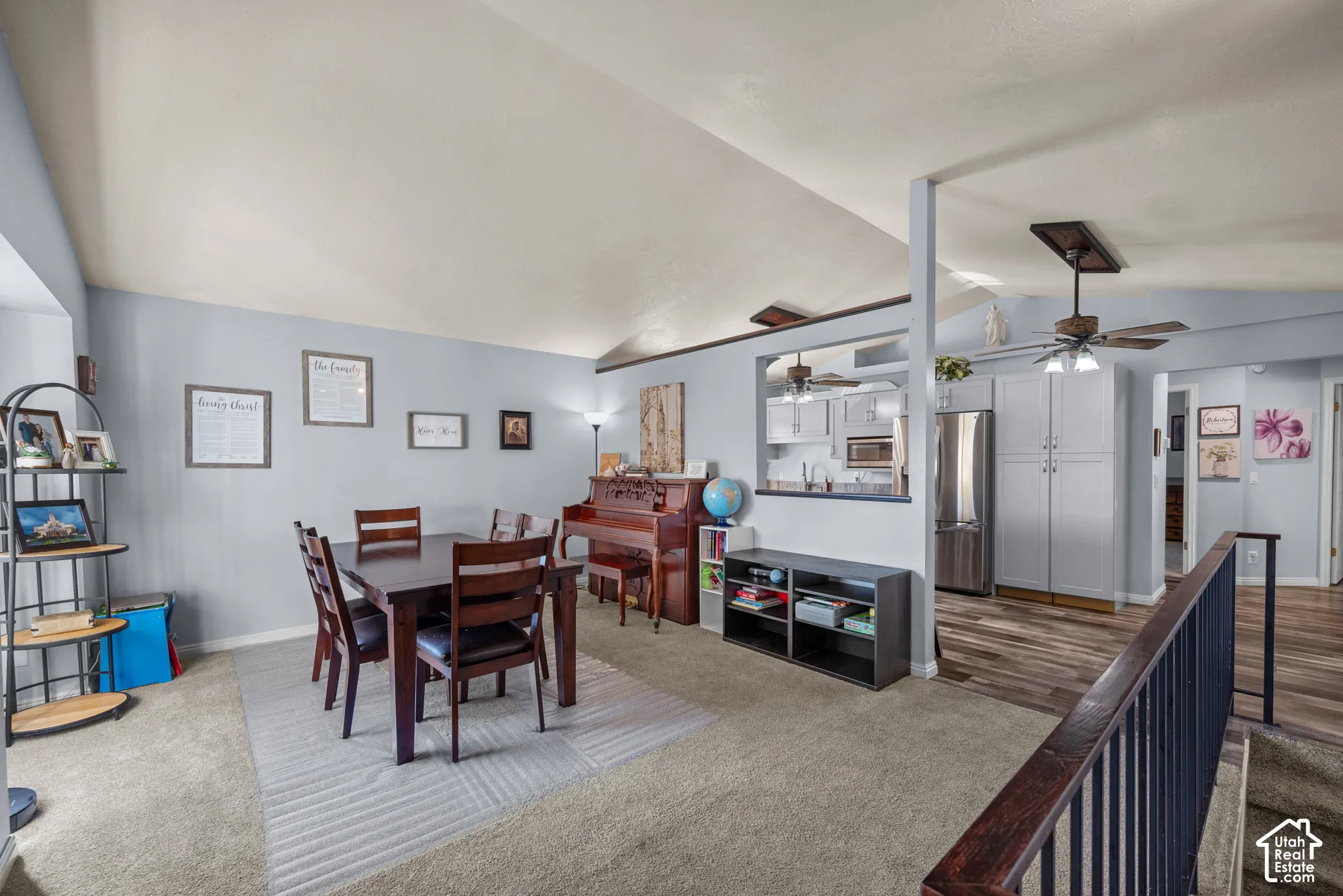 Vaulted ceilings with recessed lighting, pass-through kitchen opening, wood-finish flooring, and metal railing staircase