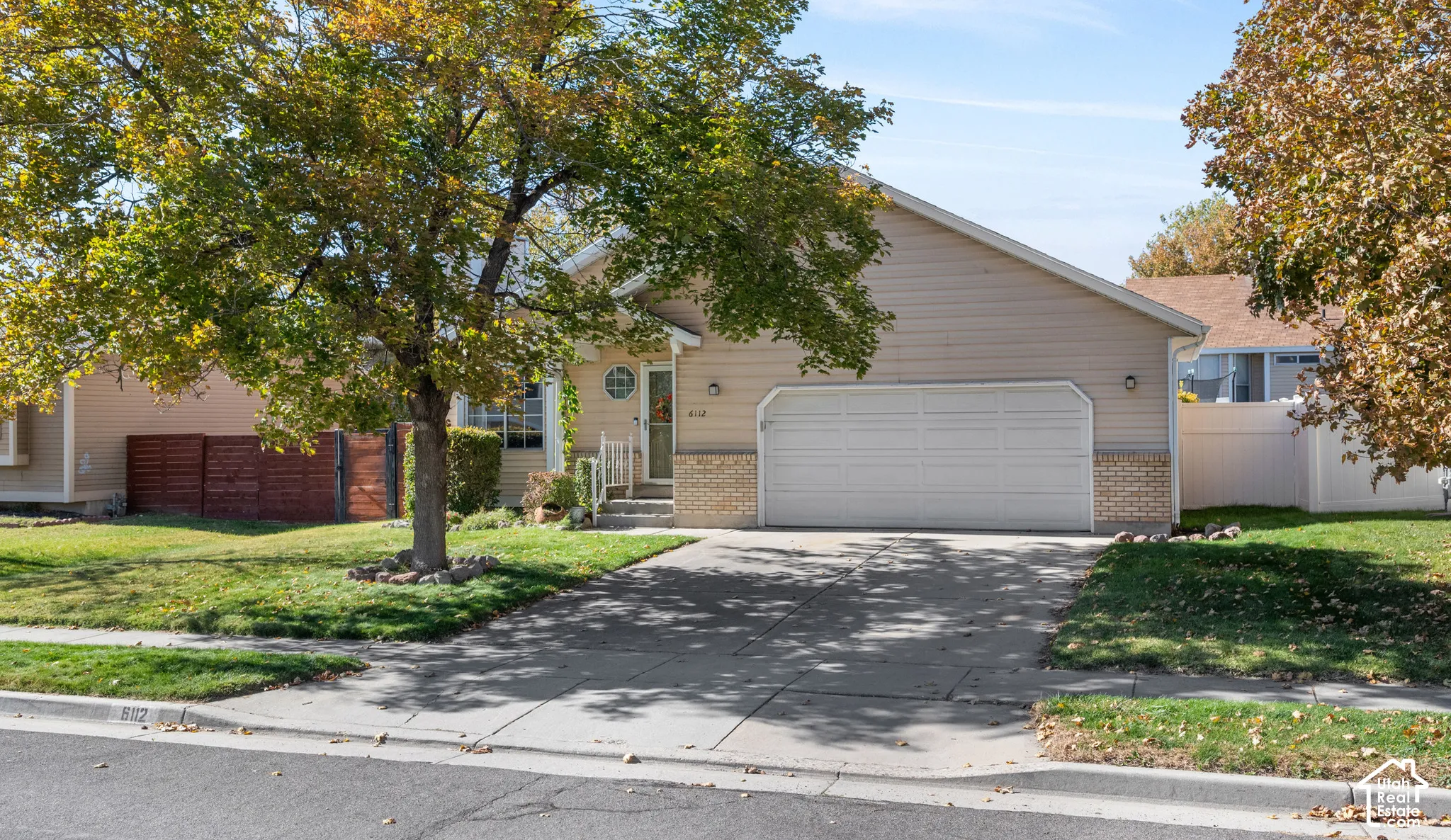 Single-story residence featuring light-colored horizontal siding, brick exterior accents, an attached two-car garage, and a concrete driveway
