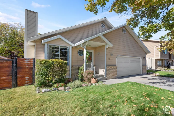 Split-level exterior featuring horizontal siding, brick masonry detailing, an attached garage, and a chimney