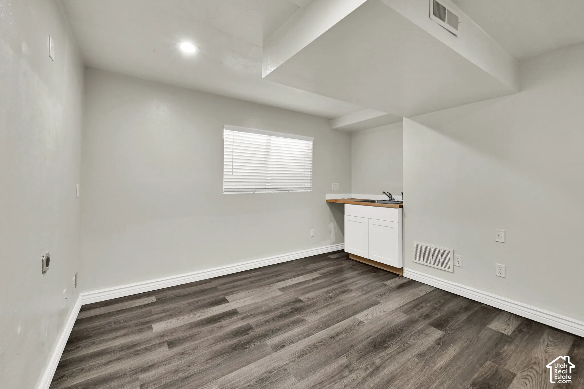 Wood-finish flooring, white shaker-style cabinetry, integrated sink, and recessed lighting