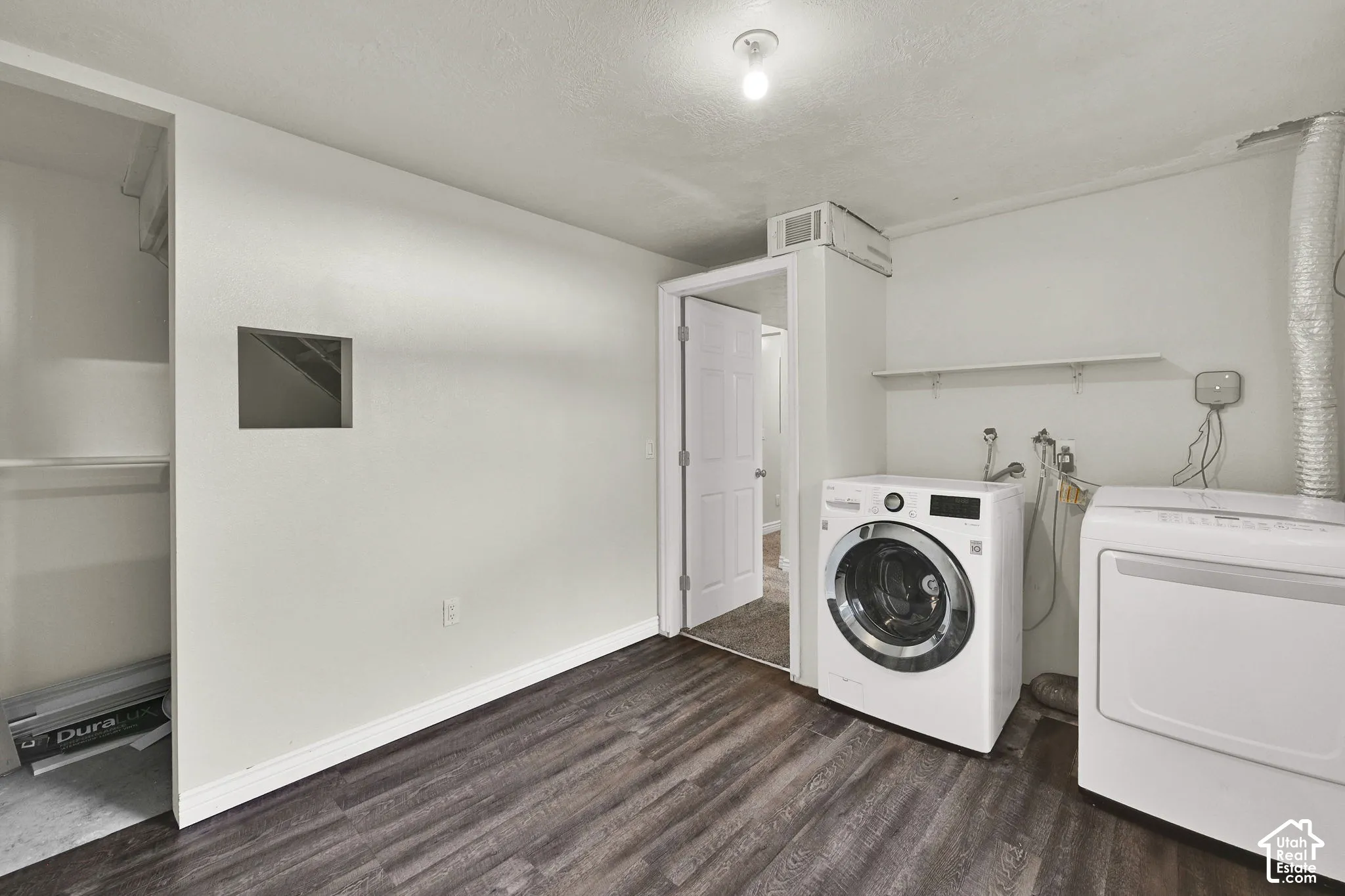 Laundry room featuring wood-finish flooring, white walls, a built-in wall shelf, and a flush-mount ceiling light