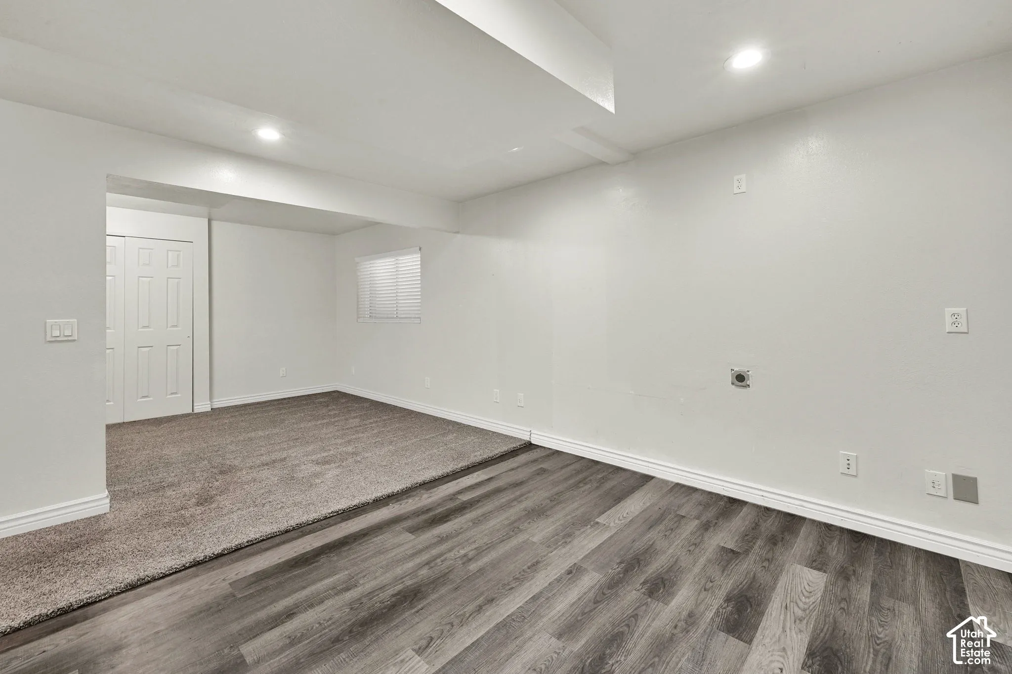 Neutral interior space featuring wood-finish flooring, plush carpeting, recessed lighting, and a dual-panel closet