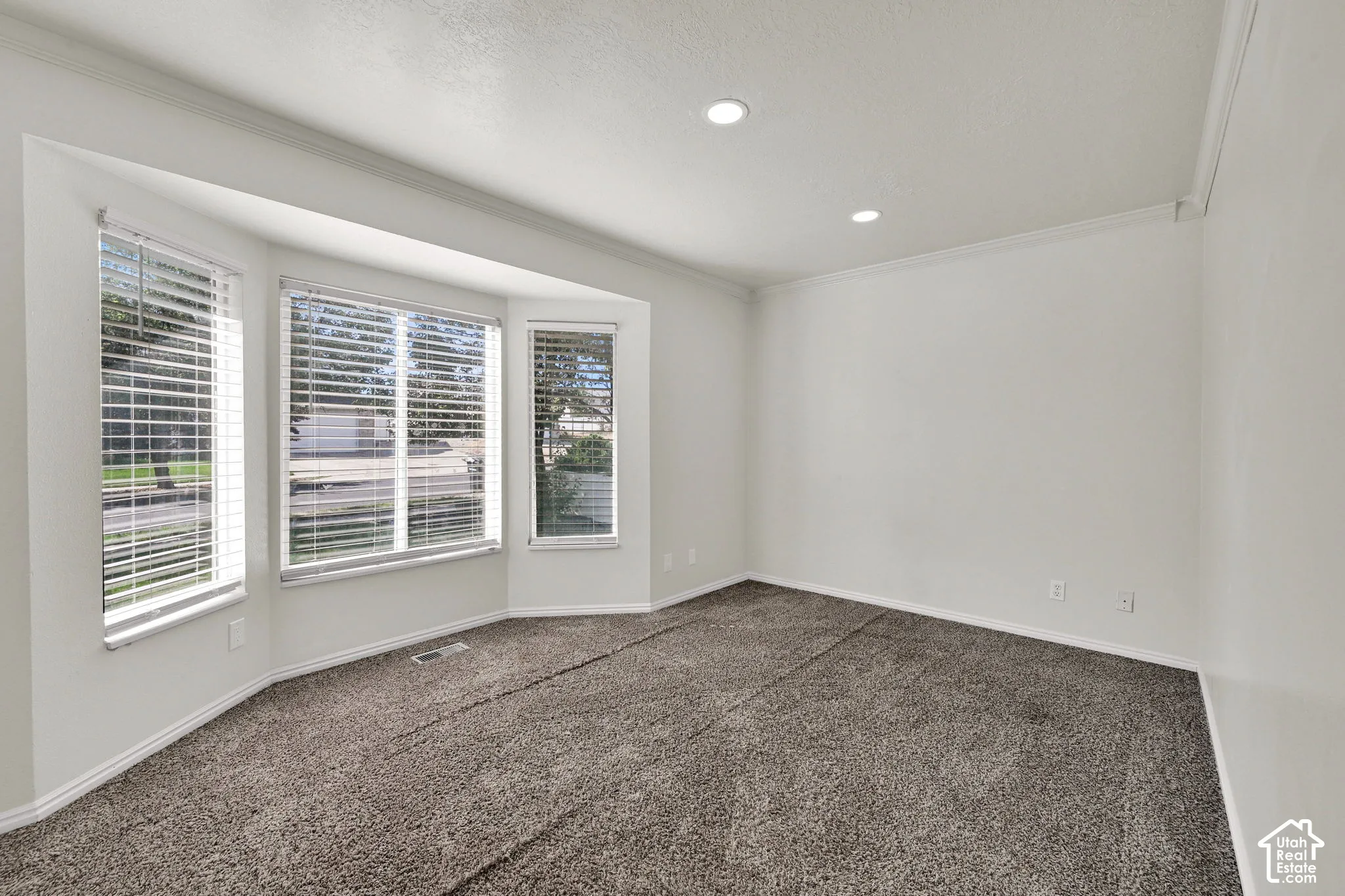 Bay window featuring multi-pane glass, neutral wall-to-wall carpeting, recessed ceiling lighting, and crown molding