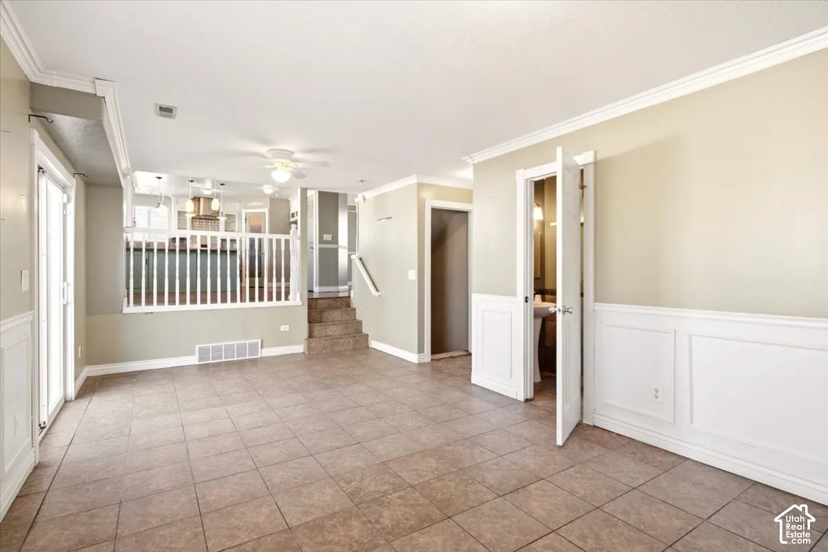 Tiled flooring, white wainscoting, crown molding, and a white wood railing