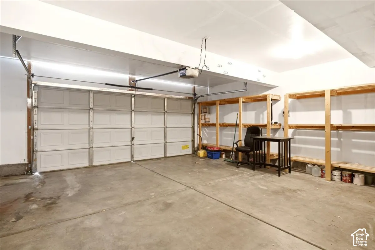 Garage featuring a sectional overhead door, concrete flooring, and built-in wooden shelving units