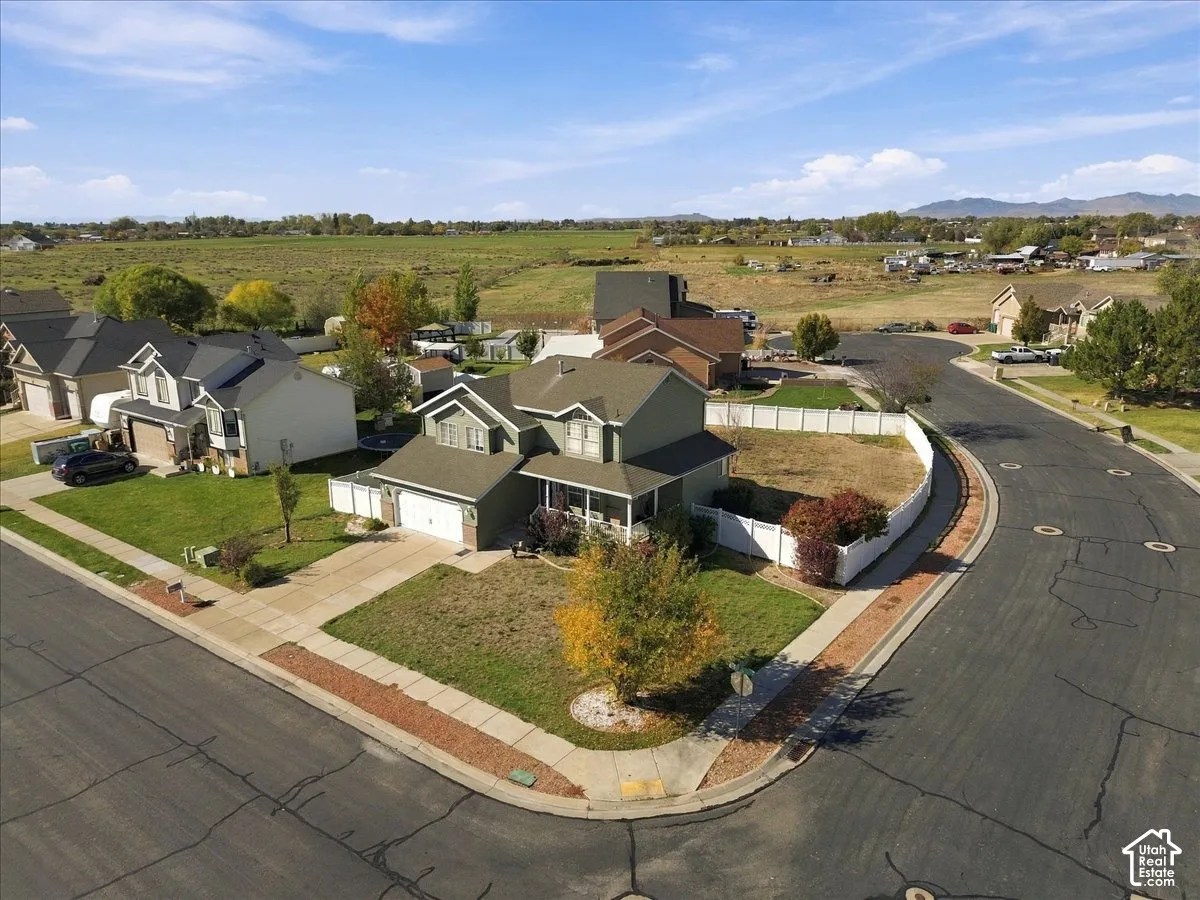 Two-story residence situated on a corner lot featuring an attached two-car garage, white vinyl perimeter fencing, and a front porch