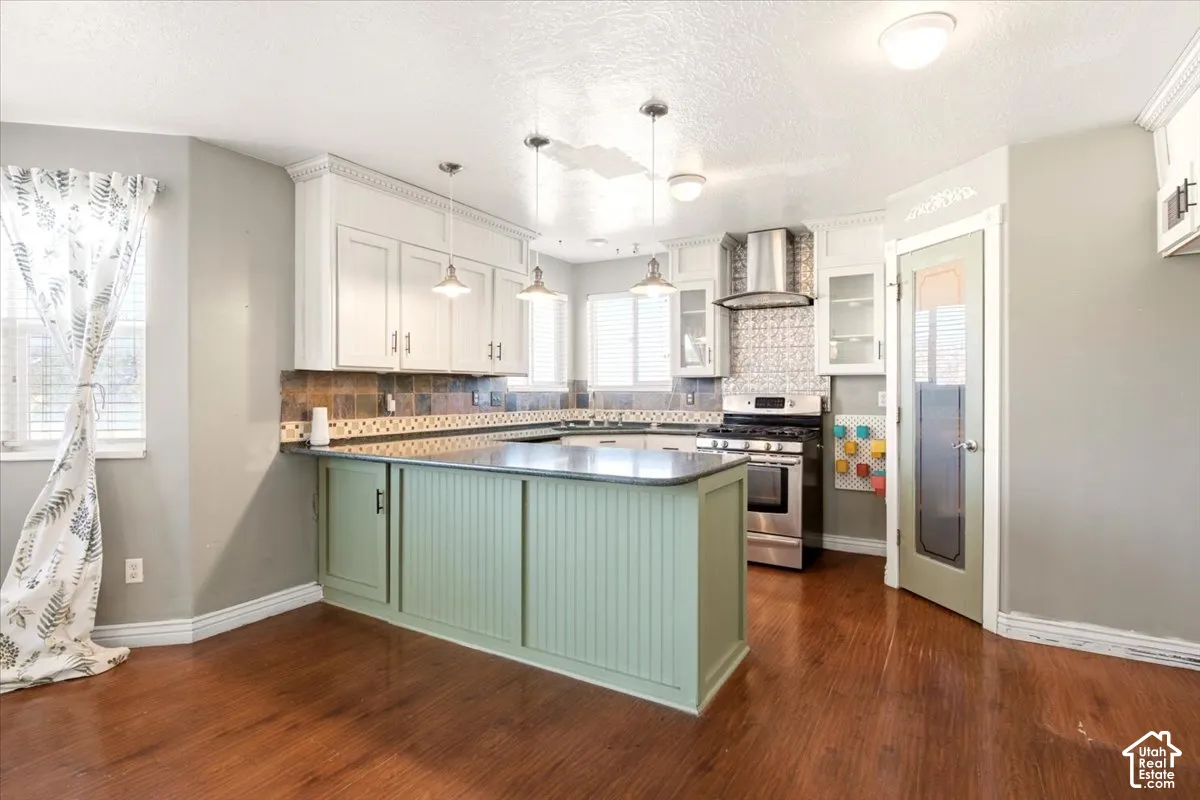 Kitchen featuring wood-finish flooring, white upper cabinetry, a green beadboard island, stainless steel range with overhead hood, and stone-tile backsplash