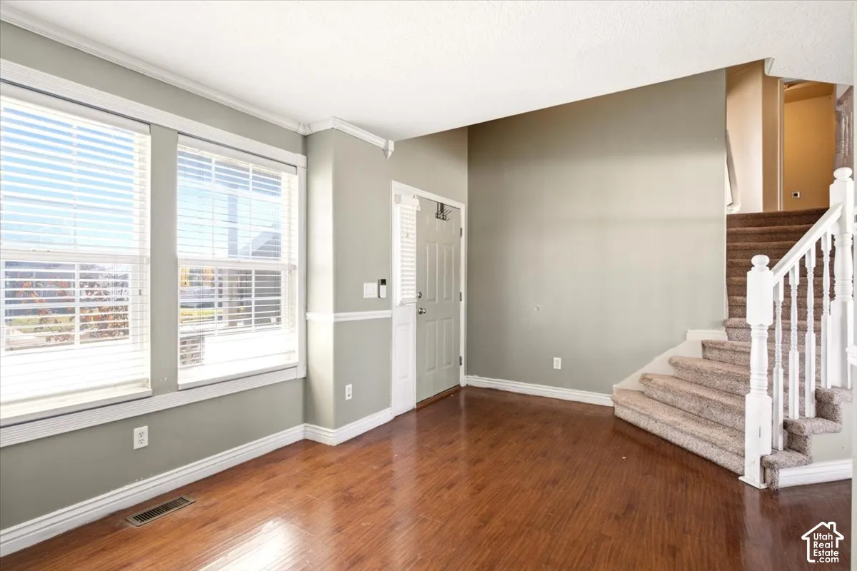 Interior space featuring wood-finish flooring, white crown molding, chair rail trim, and a staircase with a white balustrade