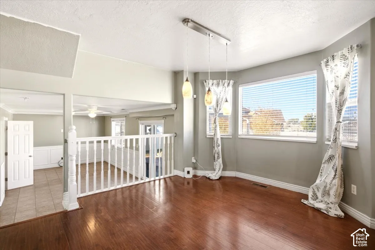 Wood-finish flooring, white spindle railing, bay window, and three-light pendant fixture