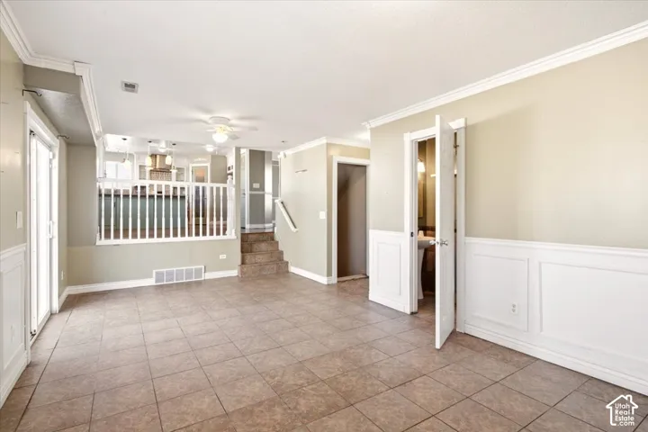Tiled flooring, white wainscoting, crown molding, and a white wood railing