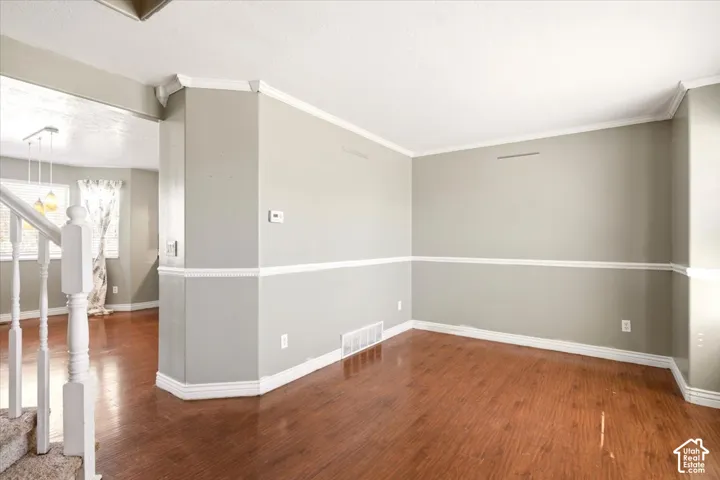 Wood-finish flooring, decorative chair rail molding, and white spindle staircase railing