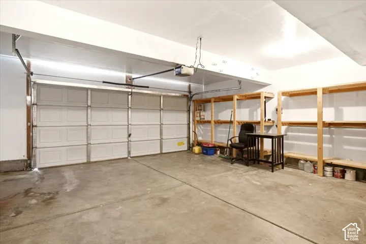 Garage featuring a sectional overhead door, concrete flooring, and built-in wooden shelving units