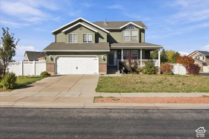 Two-story residence featuring horizontal siding, brick-veneer accents, an attached two-car garage, and a covered front porch with white railing