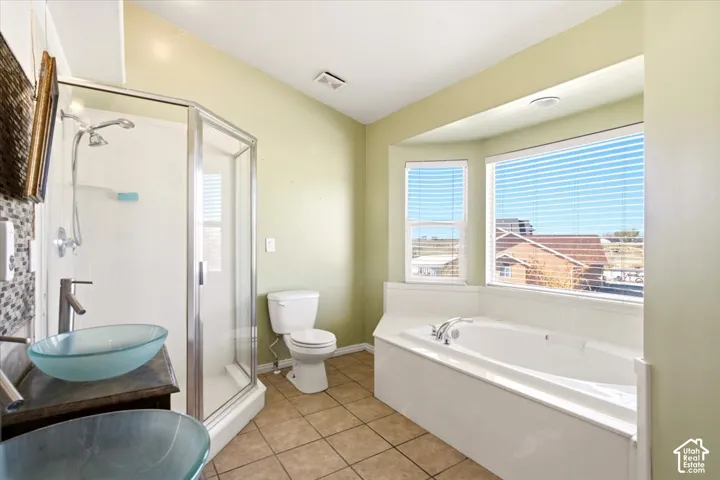 Bathroom featuring a dual-basin vanity with glass vessel sinks, a glass-enclosed shower, a deep soaking tub set within a bay window alcove, and tile flooring