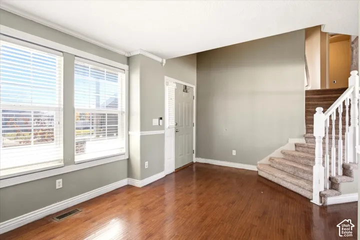 Interior space featuring wood-finish flooring, white crown molding, chair rail trim, and a staircase with a white balustrade