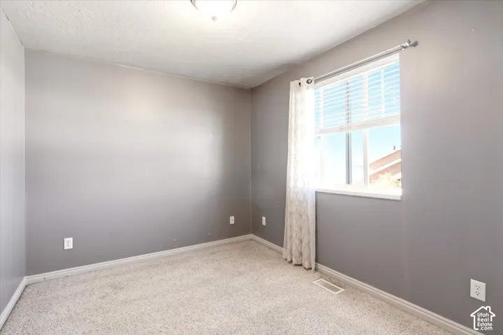 Room featuring neutral wall tones, wall-to-wall carpeting, and a window with blinds
