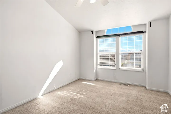 Room featuring vaulted ceilings, neutral carpeting, dual-pane windows, and an arched transom window