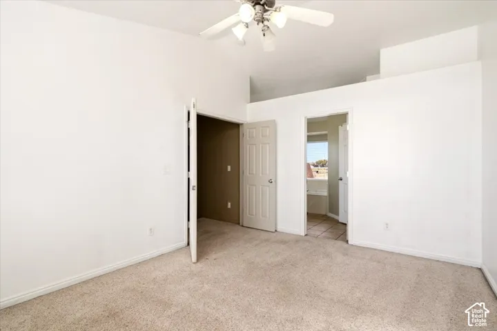Vaulted ceiling, neutral wall tones, carpeted flooring, and a multi-bulb ceiling fan fixture