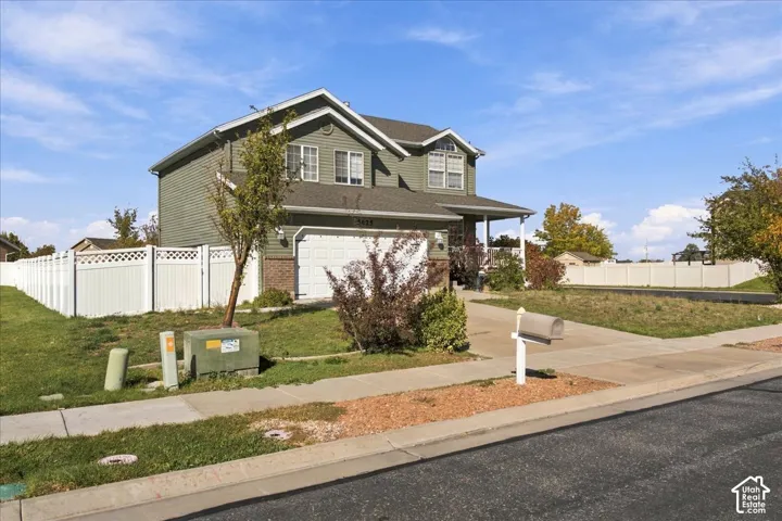 Two-story home with horizontal siding, a gabled roofline, an attached two-car garage, and a white privacy fence