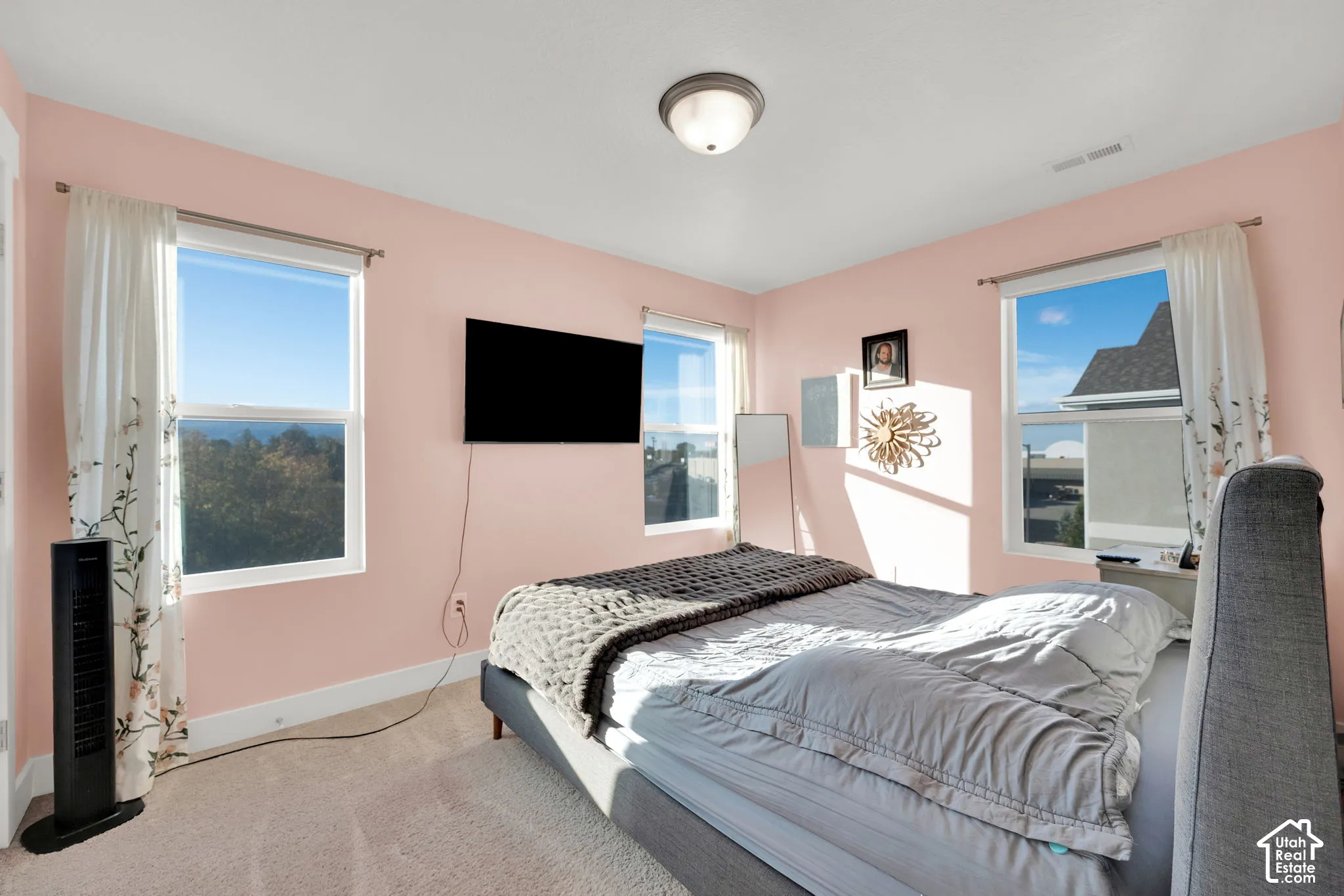 Neutral wall color with three windows providing natural lighting and a flush-mount ceiling light fixture