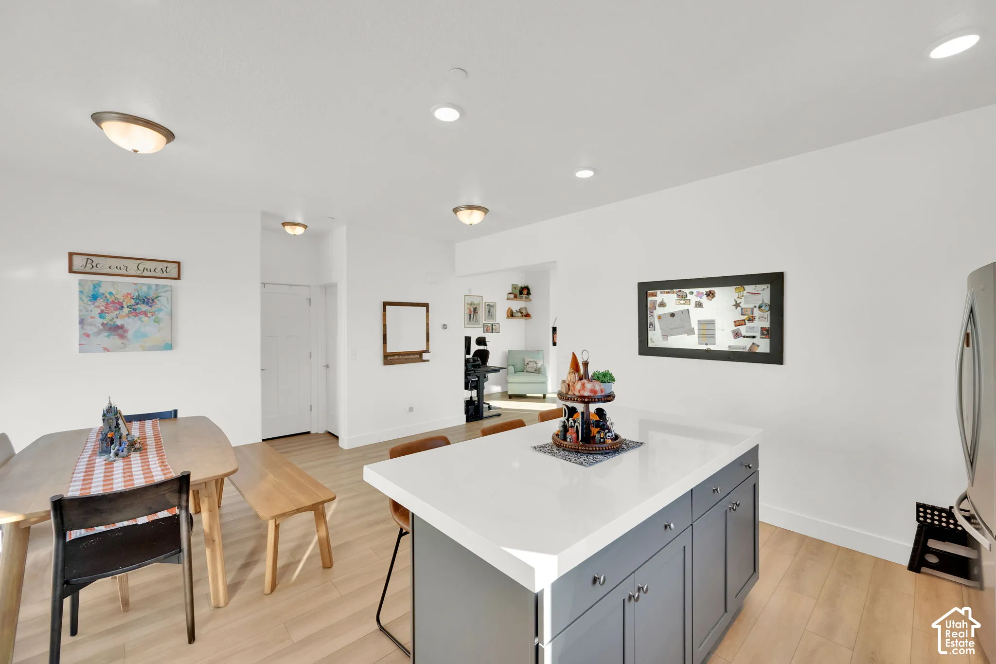 Center island featuring a white countertop and charcoal cabinetry, wood-finish flooring, and recessed ceiling lighting