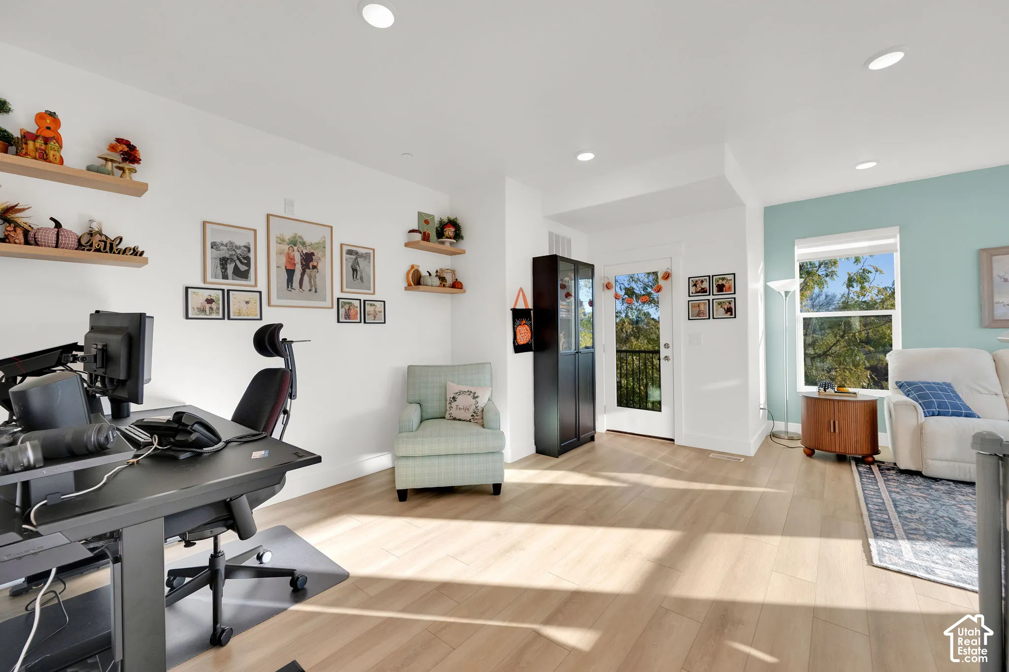 Light-filled interior featuring wood-finish flooring, recessed lighting, built-in wall shelving, and a glass-paneled exterior door