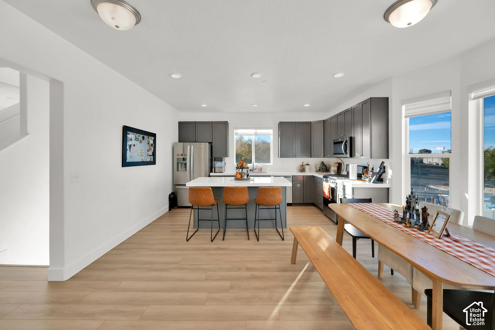 Kitchen featuring grey cabinetry, white countertops, a central island, stainless steel appliances, and wood-finish flooring