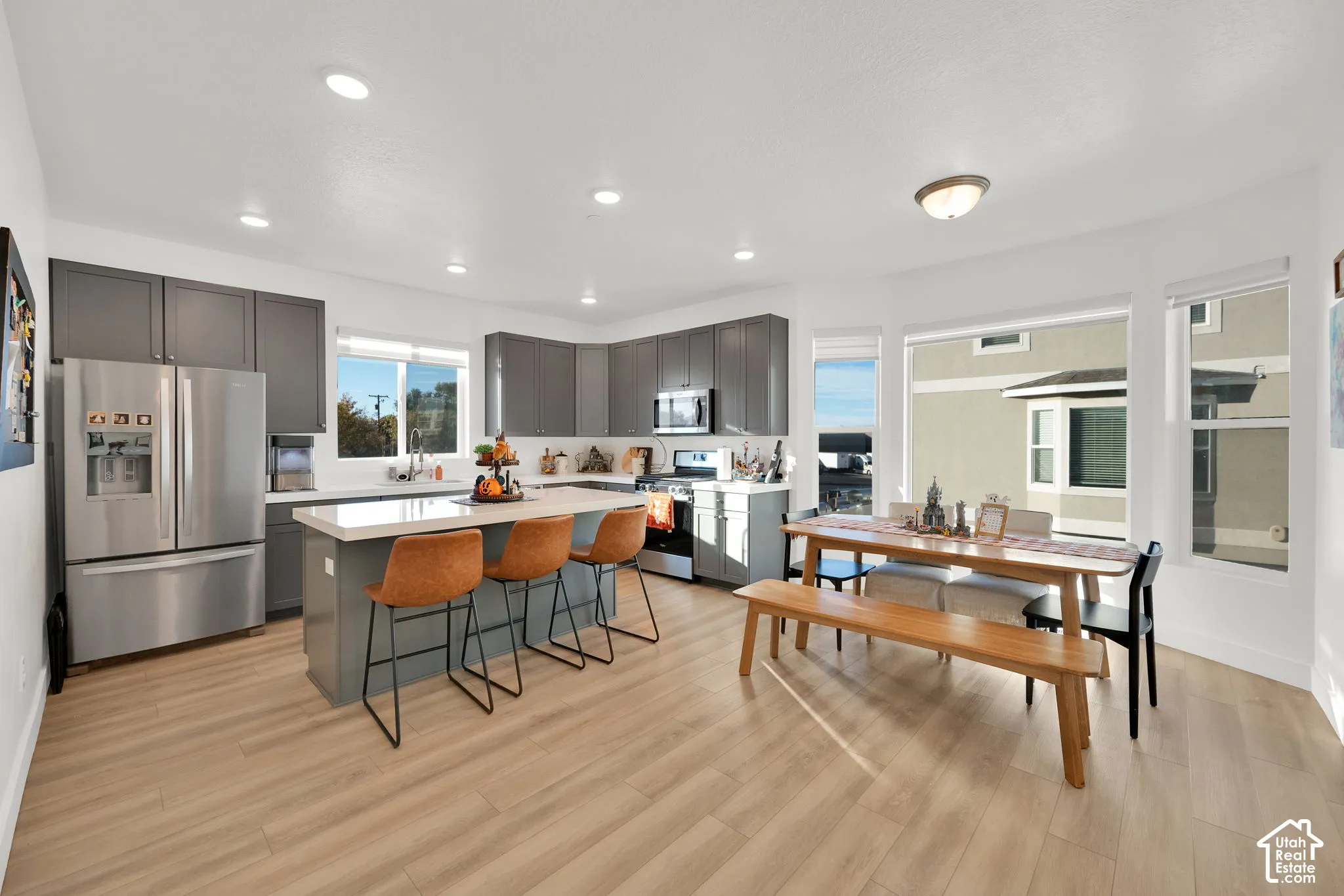 Kitchen featuring charcoal cabinetry, quartz countertops, a central island with bar seating, stainless steel appliances, and wood-finish flooring