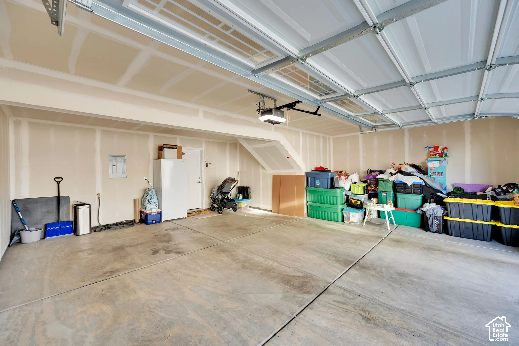 Multi-car garage featuring a concrete floor, finished drywall, overhead lighting, and an automated garage door opener