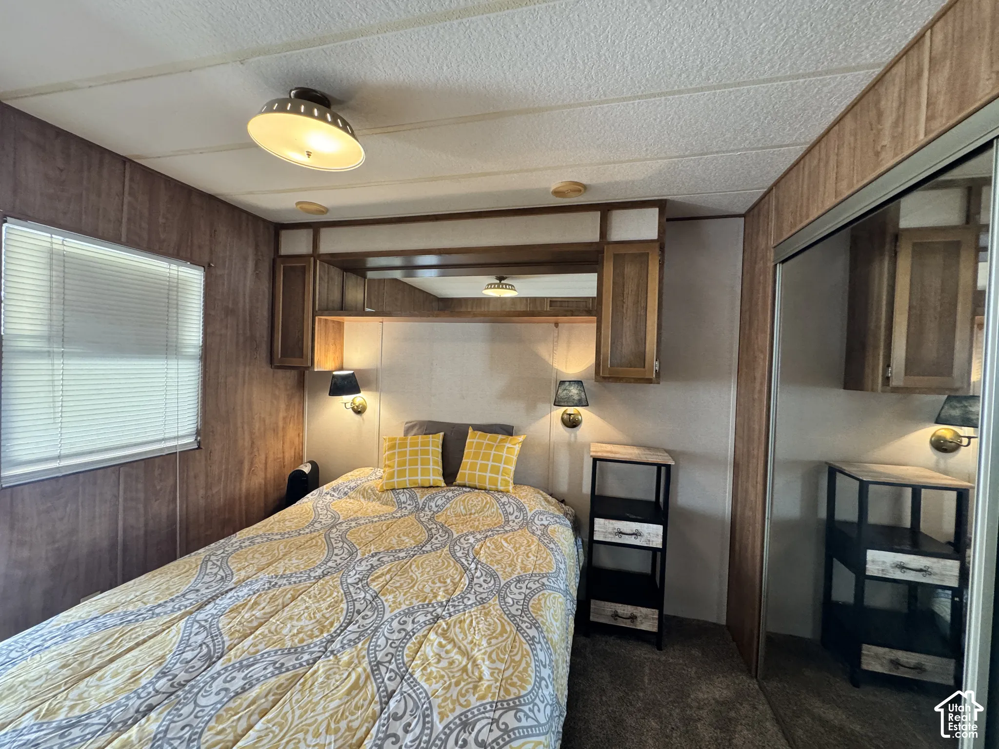 Built-in wooden cabinetry featuring overhead storage, a central mirror, and integrated wall-mounted light fixtures, complemented by a sliding mirror-panel closet