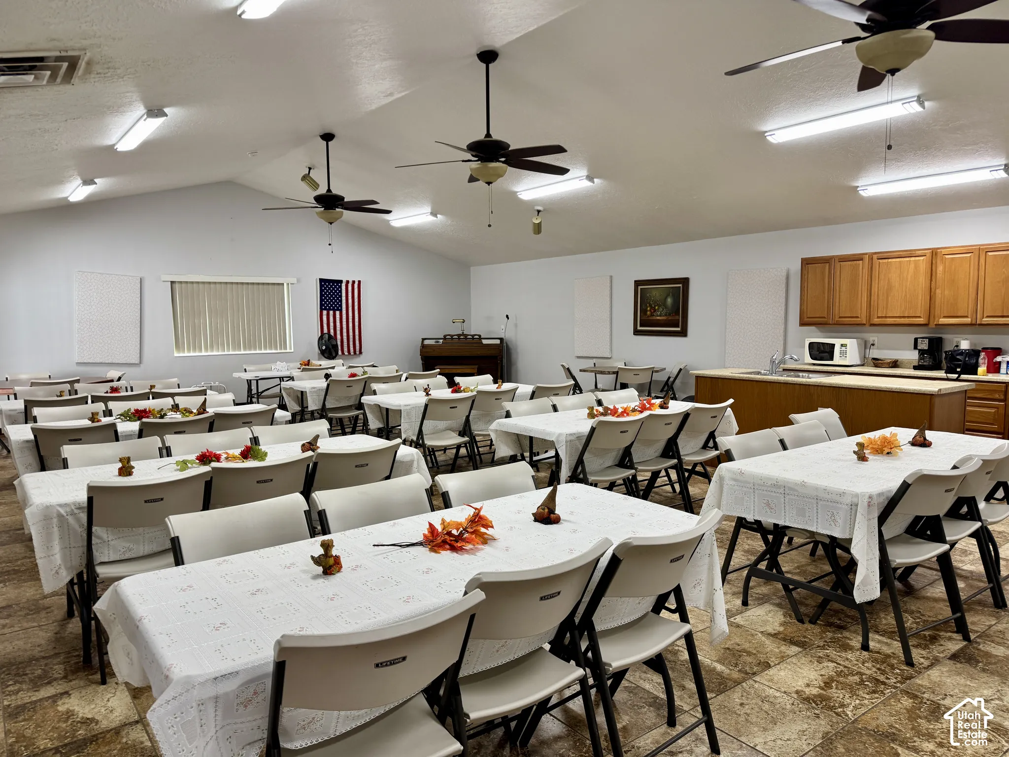 Vaulted ceilings featuring multiple ceiling fans and linear lighting, complemented by tile flooring and built-in cabinetry with a countertop workspace