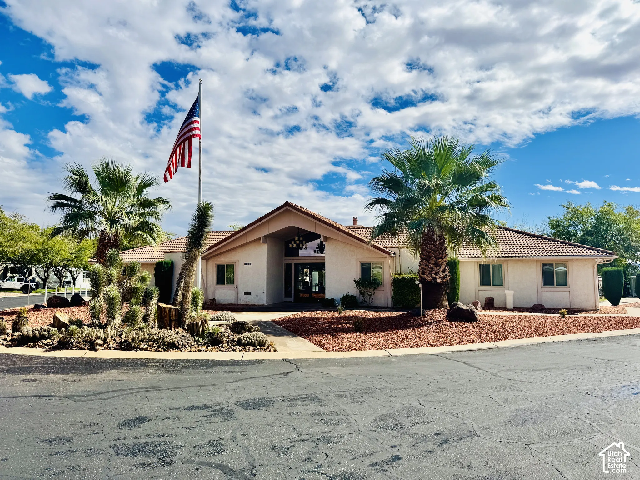 Single-story exterior featuring a gabled roofline, light-toned siding, tile roofing, and desert-inspired landscaping