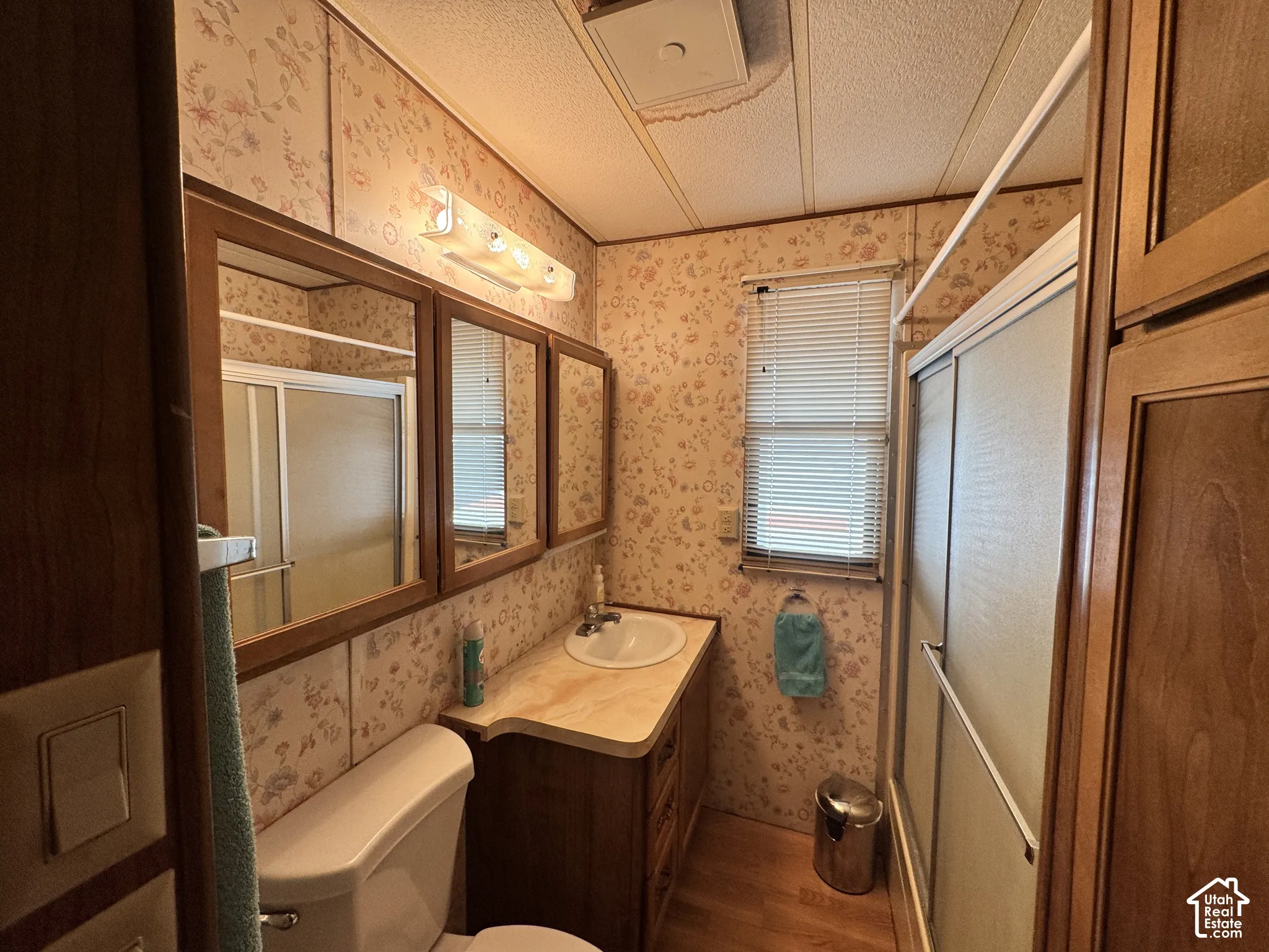 Bathroom featuring wood-finish cabinetry, a built-in vanity with a circular sink, dual wood-framed mirrors, and a glass-enclosed shower