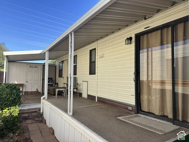 Covered exterior porch featuring textured flooring, aluminum siding, sliding glass door, and integrated storage unit