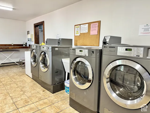 Utility area featuring tile flooring, a white porcelain utility sink, and multiple front-load coin-operated washing machines