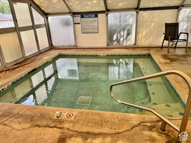 Enclosed indoor pool with a metal-framed structure, opaque glass paneling, and a stainless steel grab rail