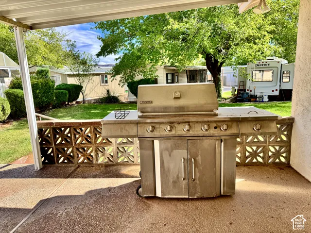 Covered patio featuring a concrete floor, decorative concrete block perimeter wall, and built-in stainless steel grill