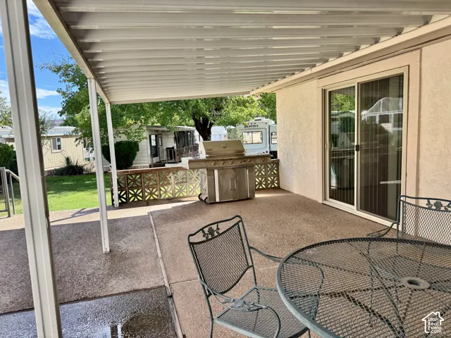 Covered concrete patio featuring a built-in stainless steel grill and a decorative breeze block privacy wall