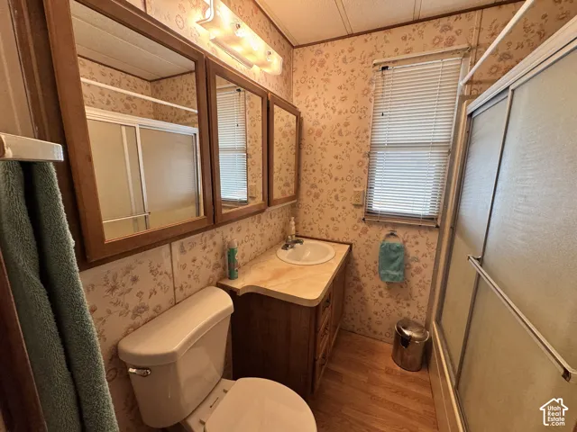 Bathroom featuring a wood vanity with a solid-surface countertop, an integrated sink, tri-panel mirrored cabinetry, and a walk-in shower with sliding glass doors