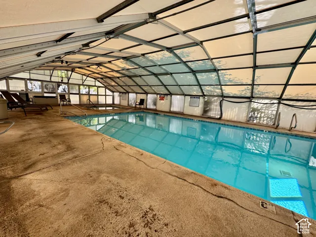 Enclosed swimming pool featuring a retractable arched metal framework, concrete decking, and integrated step entry