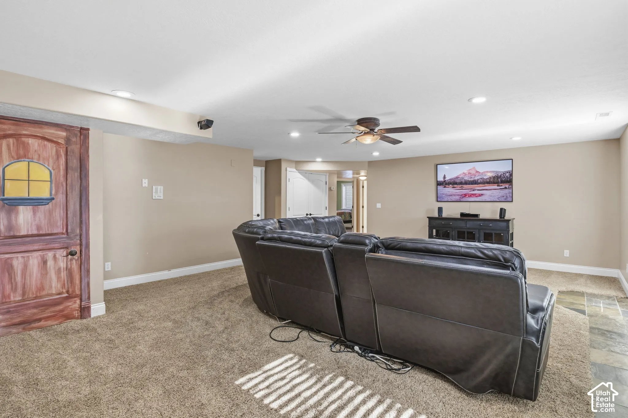 Spacious room featuring recessed lighting, a ceiling fan, neutral wall tones, wall-to-wall carpeting, and a custom wood-finish door with a decorative accent window