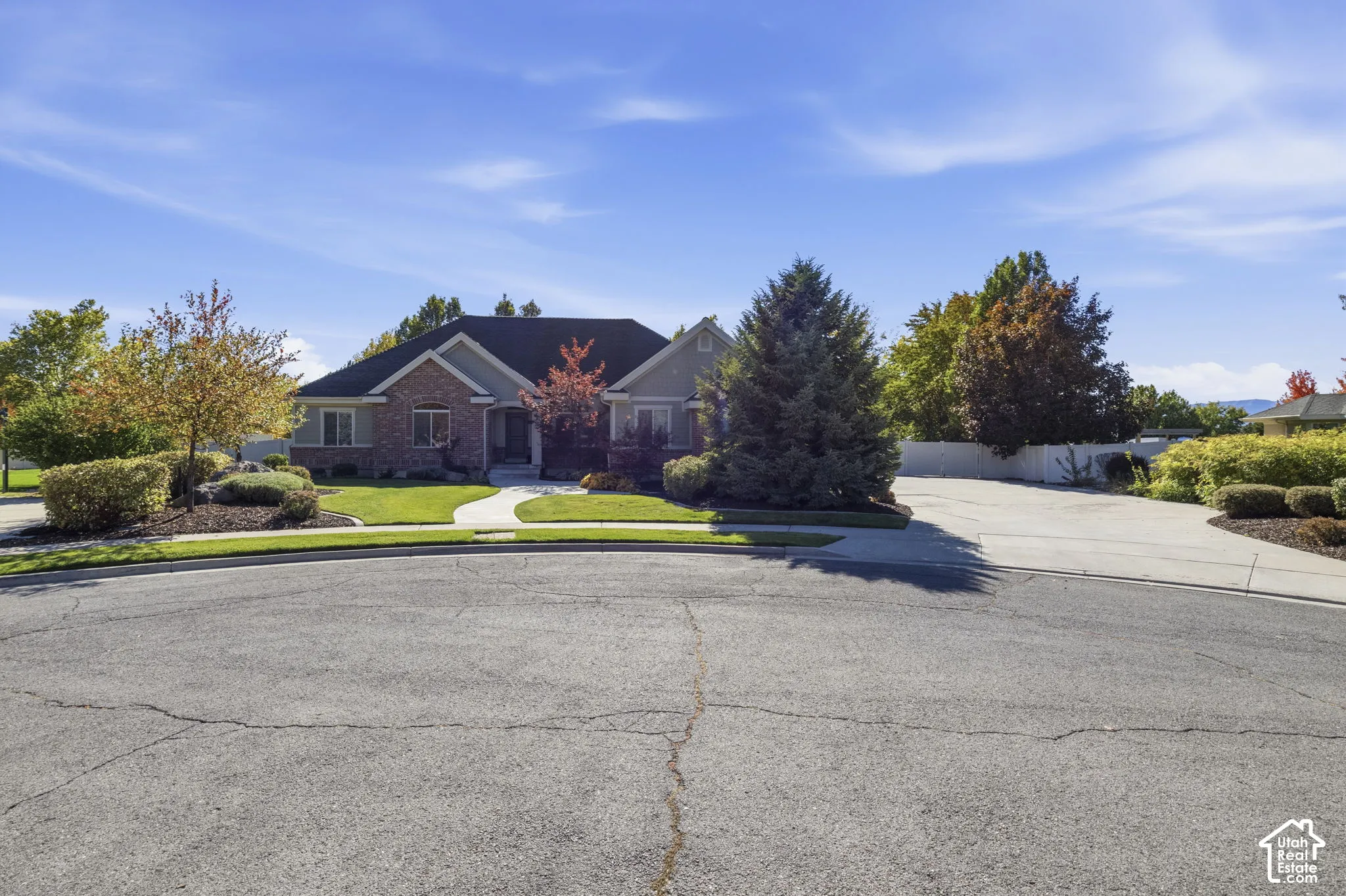 Single-story residence featuring a brick and siding exterior, multi-gabled roofline, concrete driveway, and established landscaping