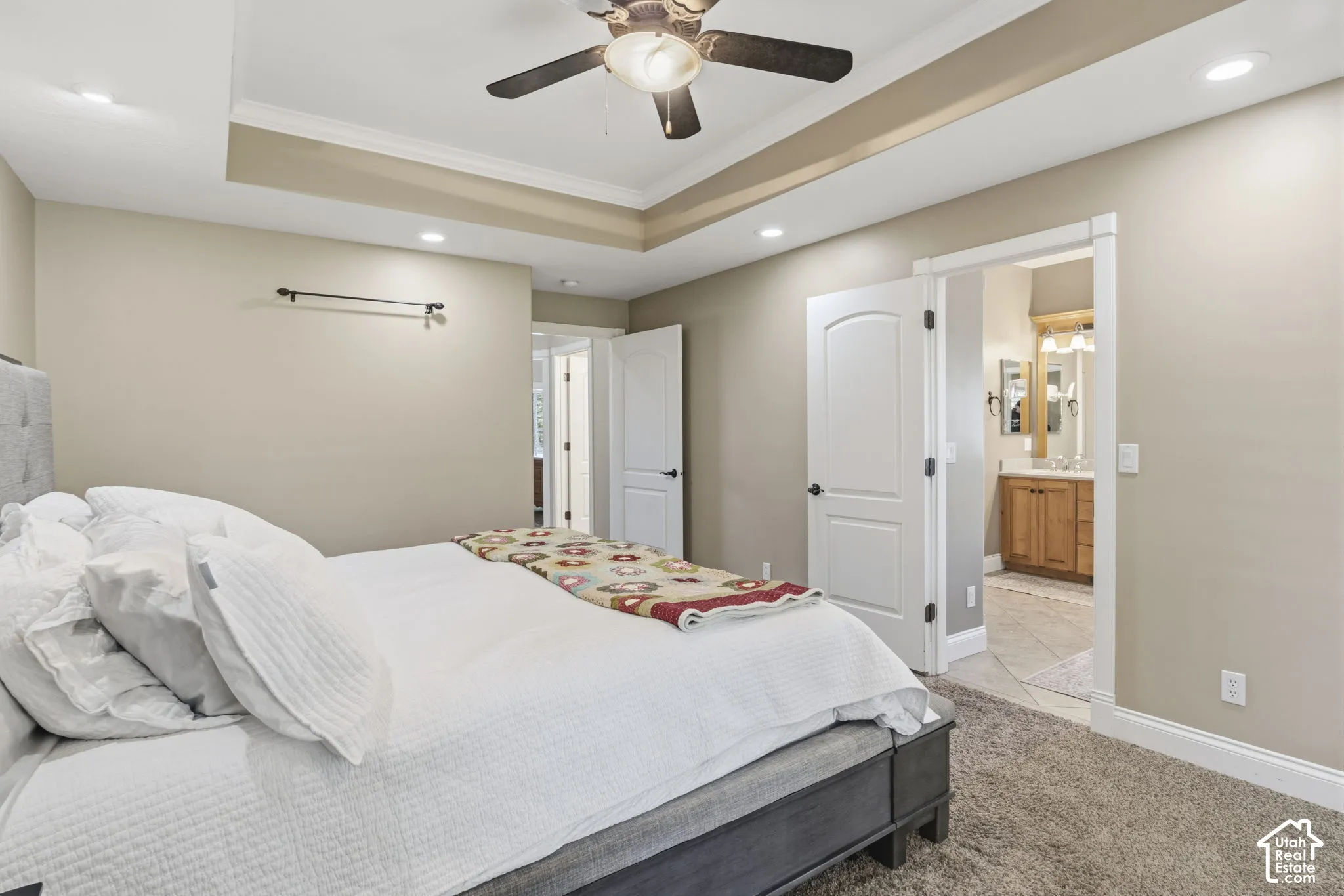 Tray ceiling featuring recessed lighting and a central ceiling fan, neutral wall tones, and interior doors with oil-rubbed bronze hardware